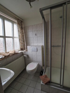 A bathroom with a bathtub, toilet, and glass shower enclosure. - Gasthof Erfurth (Sehnde)