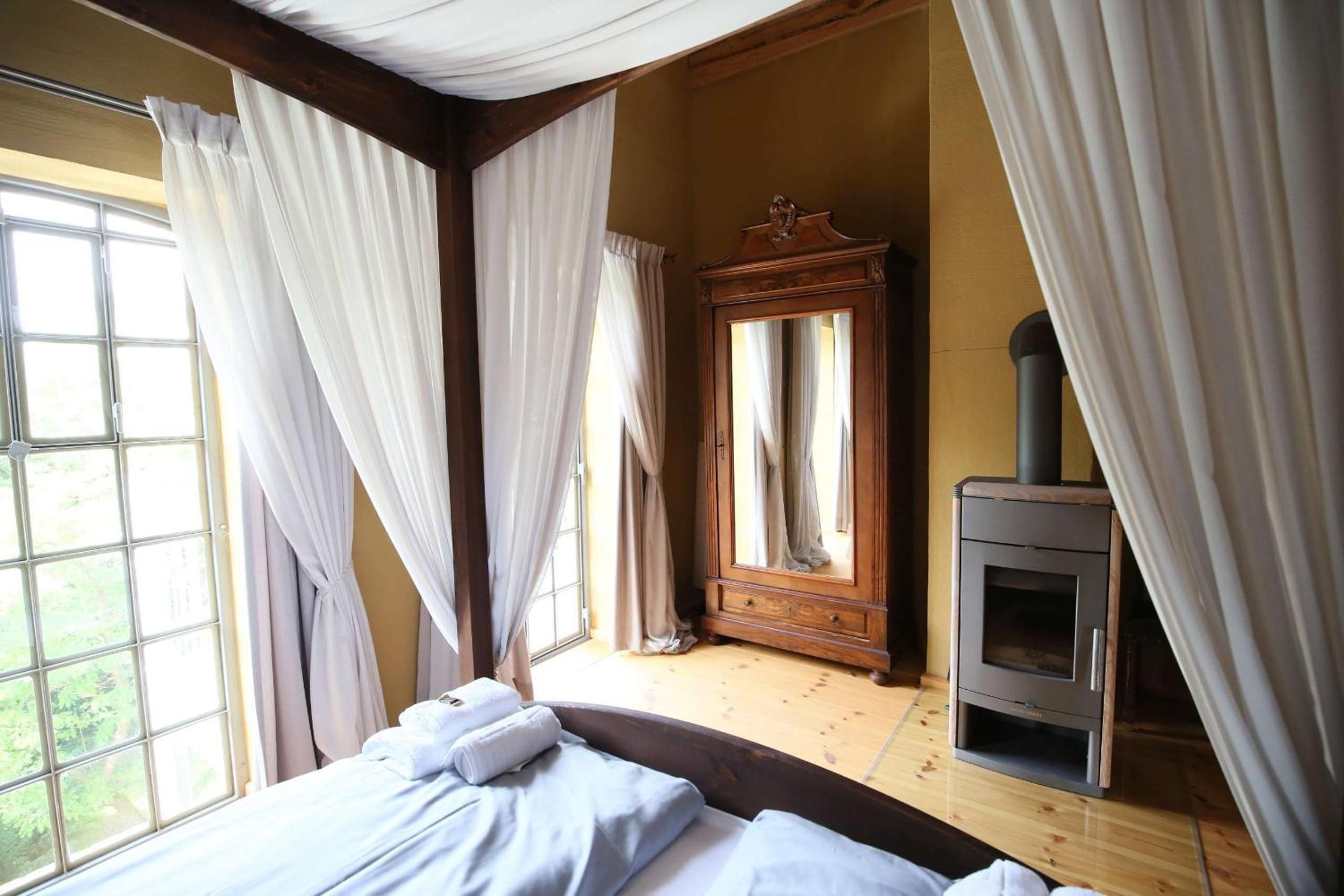 Ein Schlafzimmer mit einem Bett, einem Holzschrank, einem Spiegel und einem Kaminofen.