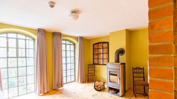 Una habitación con ventanas amplias, chimenea y pared de ladrillo.