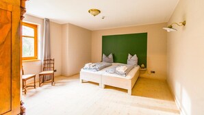 Un dormitorio con una cama, una silla, un armario, una ventana y una pared verde de acento.
