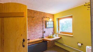 Ein Badezimmer mit Holztür, Backsteinwand, Fenster und Waschbecken.