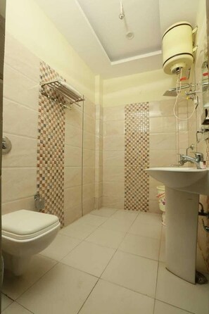 Ein Badezimmer mit Toilette, Waschbecken, Dusche und gefliesten Wänden.