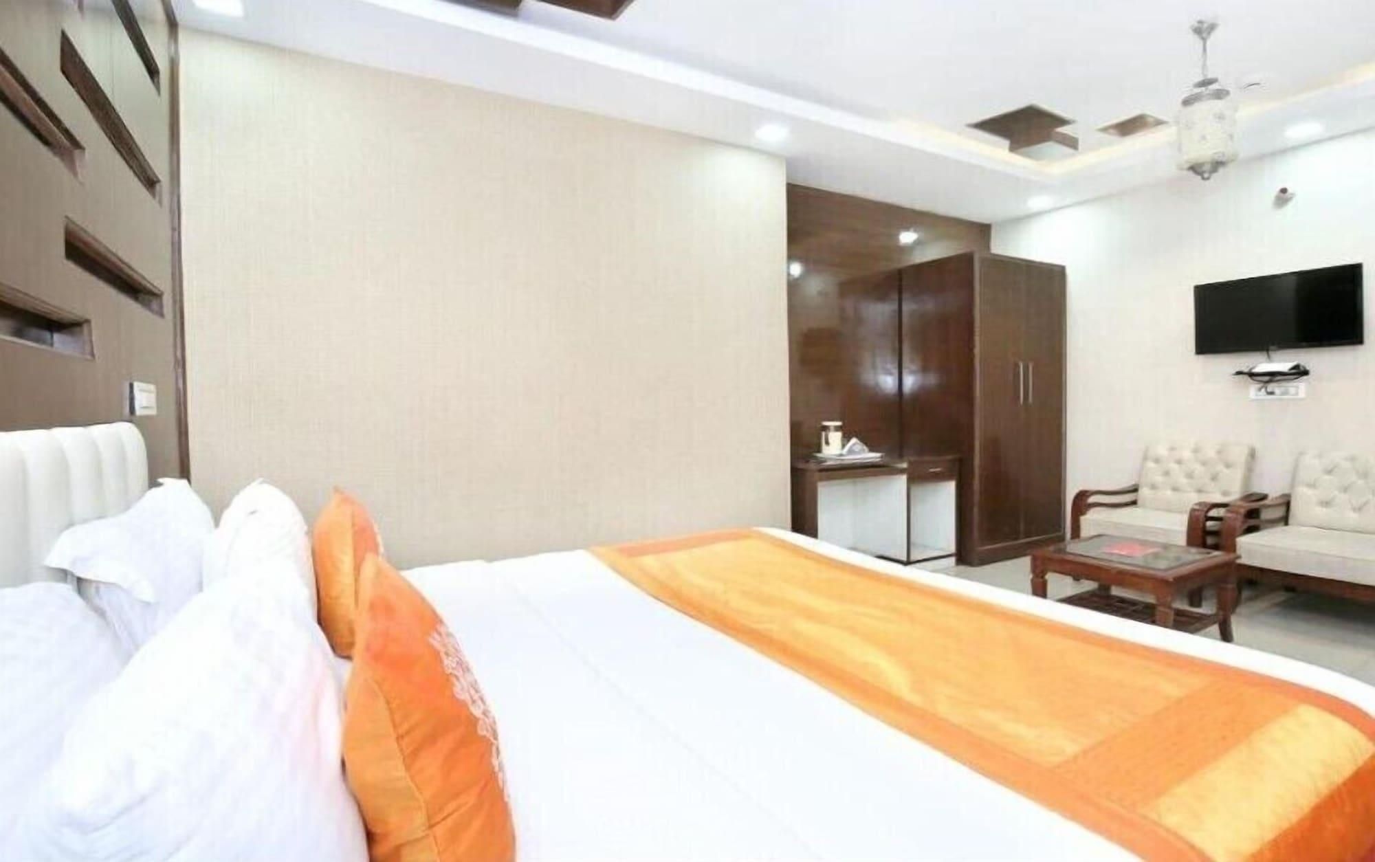 A hotel room with a bed, a desk, a wardrobe, a sofa, and a television.