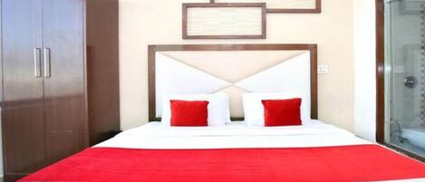 A hotel room with a bed, a wardrobe, and a glass door.