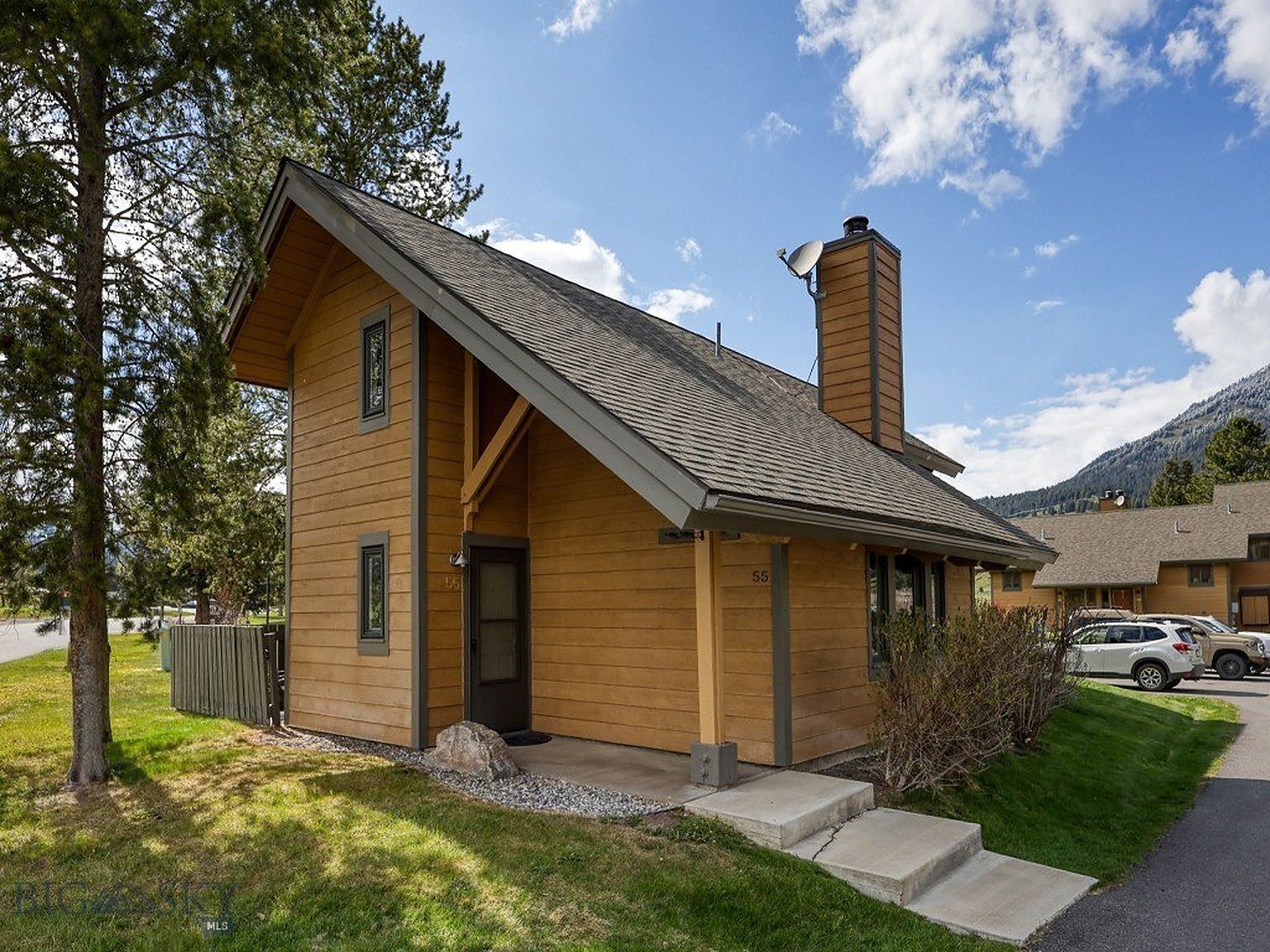 A single-story wooden house with a gabled roof, a chimney, and a front door.