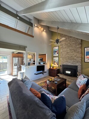 A living room with a fireplace, a television, and a dining area. - Big Sky Ski & Snowboard Escape, Cozy Fireside Nights. Black Otter 55 Basecamp. (Big Sky)
