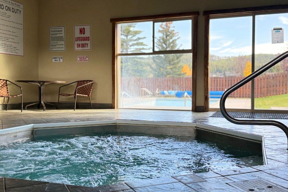 Zona de hidromasaje con vistas a una piscina y una valla de madera.