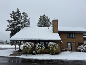 Een tweelaags huis met een sneeuwbedekte dak en een overdekte veranda.