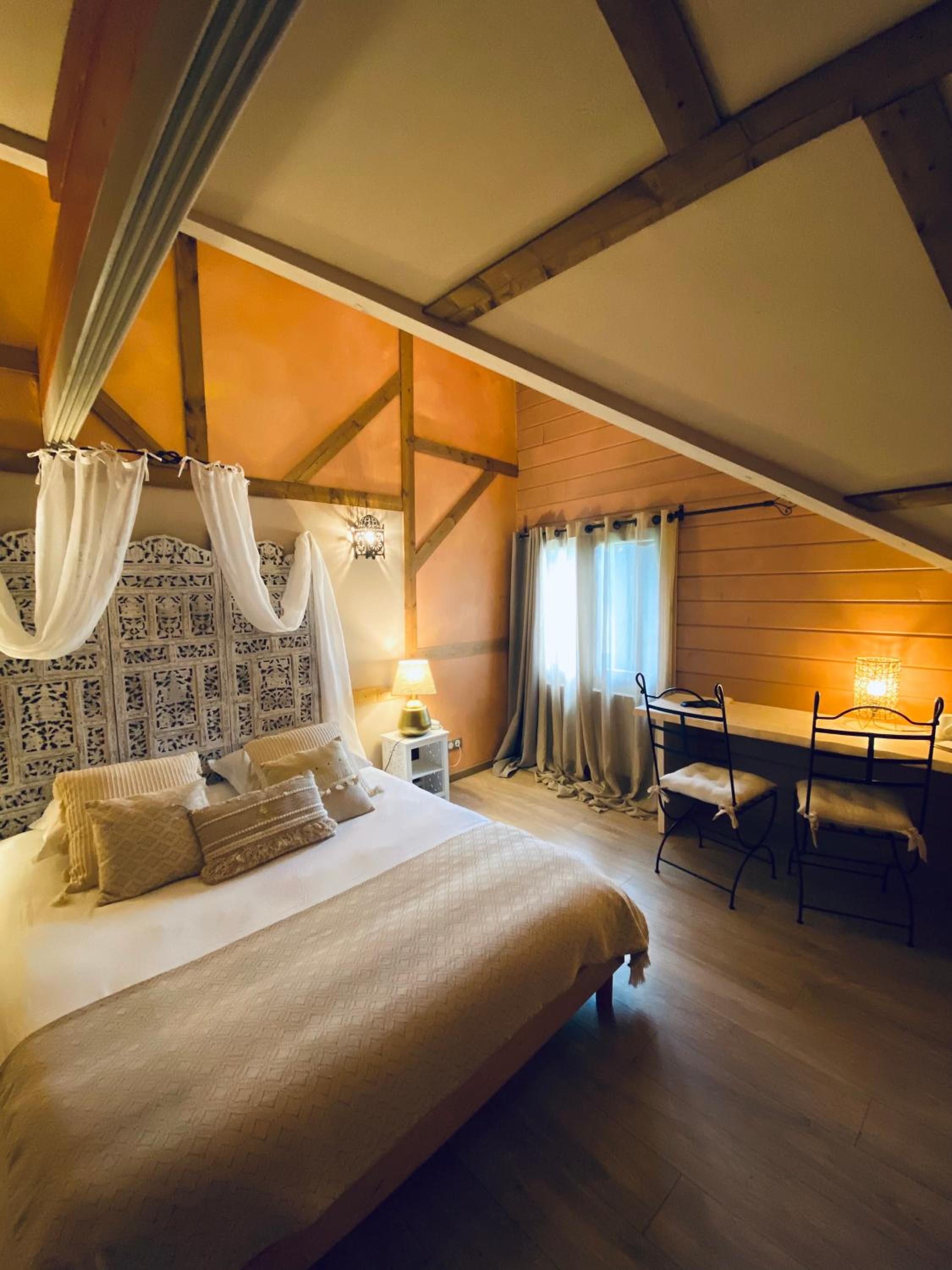 A bedroom with a large bed, a desk, and a chair.
