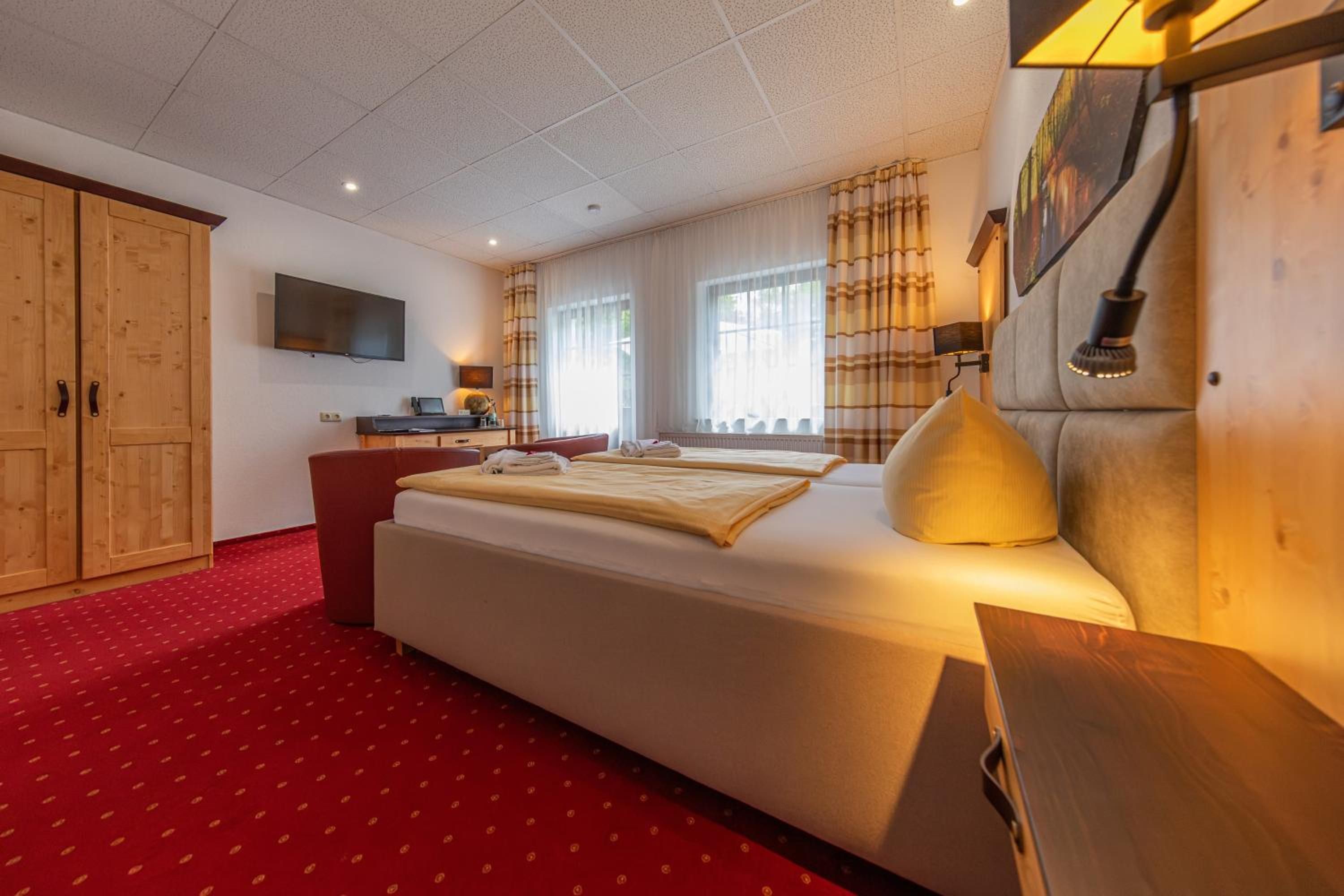 Ein Hotelzimmer mit einem großen Bett, einem Schreibtisch, einem Fernseher und einem Kleiderschrank.