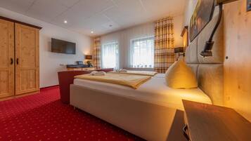 Ein Hotelzimmer mit einem großen Bett, einem Schreibtisch, einem Fernseher und einem Kleiderschrank.