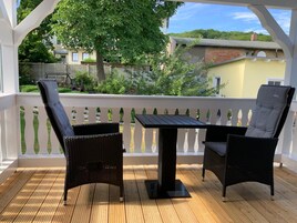 Un patio techado al aire libre con mobiliario de mimbre y una mesa.