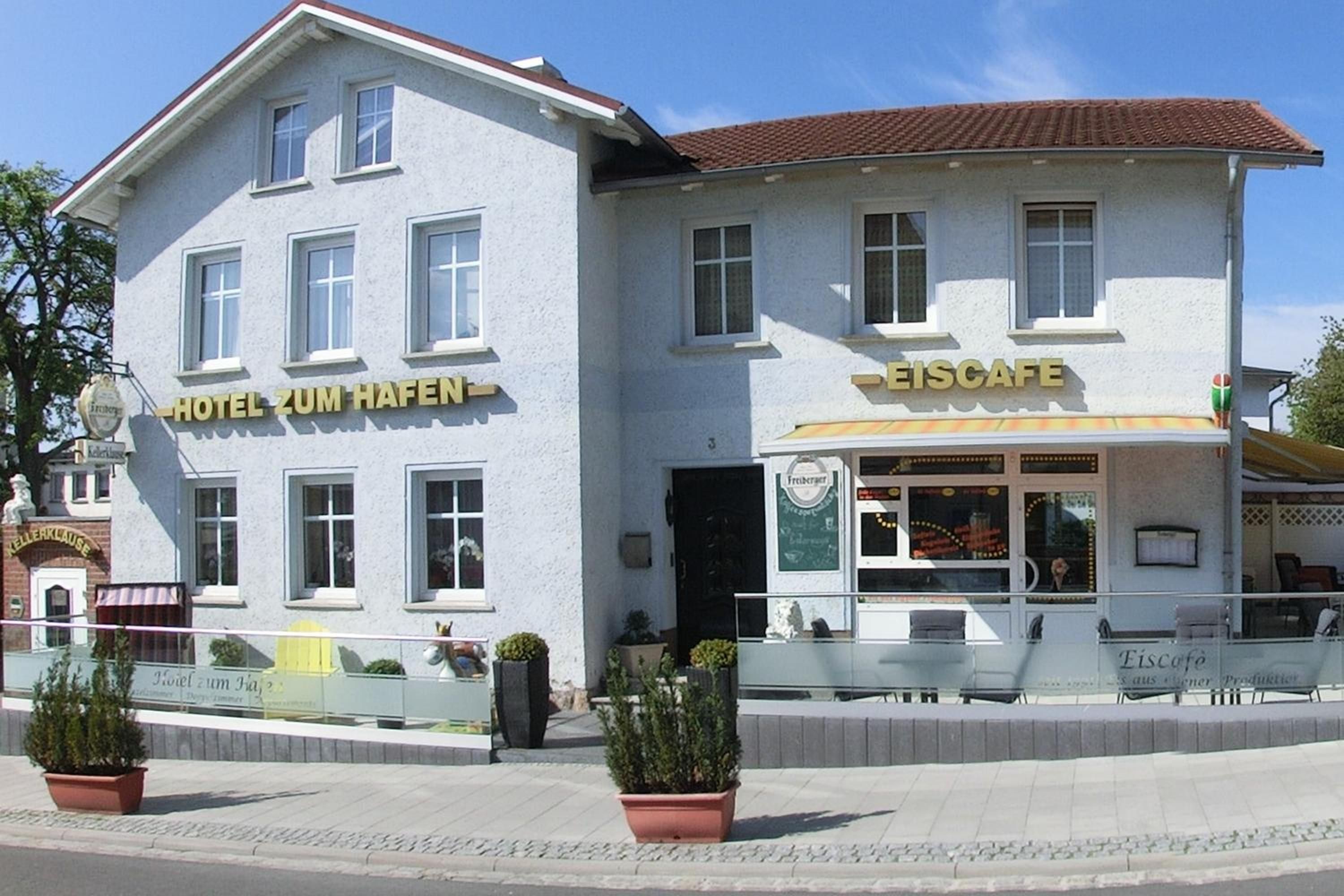 Un edificio de dos pisos con un cartel que dice 'Hotel Zum Hafen' y 'Eis cafe' en la planta baja.