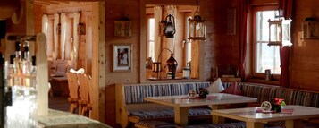 Un interior de madera acogedor con un banco, una mesa y faroles colgantes.