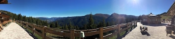 Vista panorámica de un paisaje montañoso con una valla de madera, un pabellón y un camino pavimentado.
