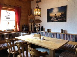 Un interno in legno con un tavolo lungo, panche e un quadro appeso al muro.
