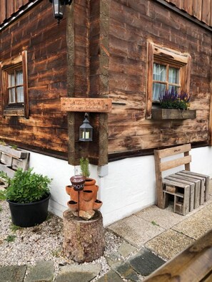 Ein rustikales Holzgebäude mit einer hölzernen Bank, einem Blumentopf und einem Holzschemel.