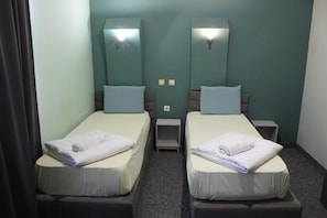 A twin room with two beds, each with a pillow and a folded towel. - Hotel Color (Asenovgrad)