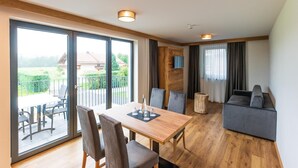 Ein modernes Interieur mit Essbereich, einer Couch und einer großen Schiebeglastür, die auf eine Terrasse im Freien führt.