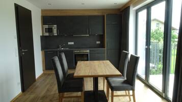 Eine moderne Küche mit dunklen Schränken, einem Holztisch und Stühlen.