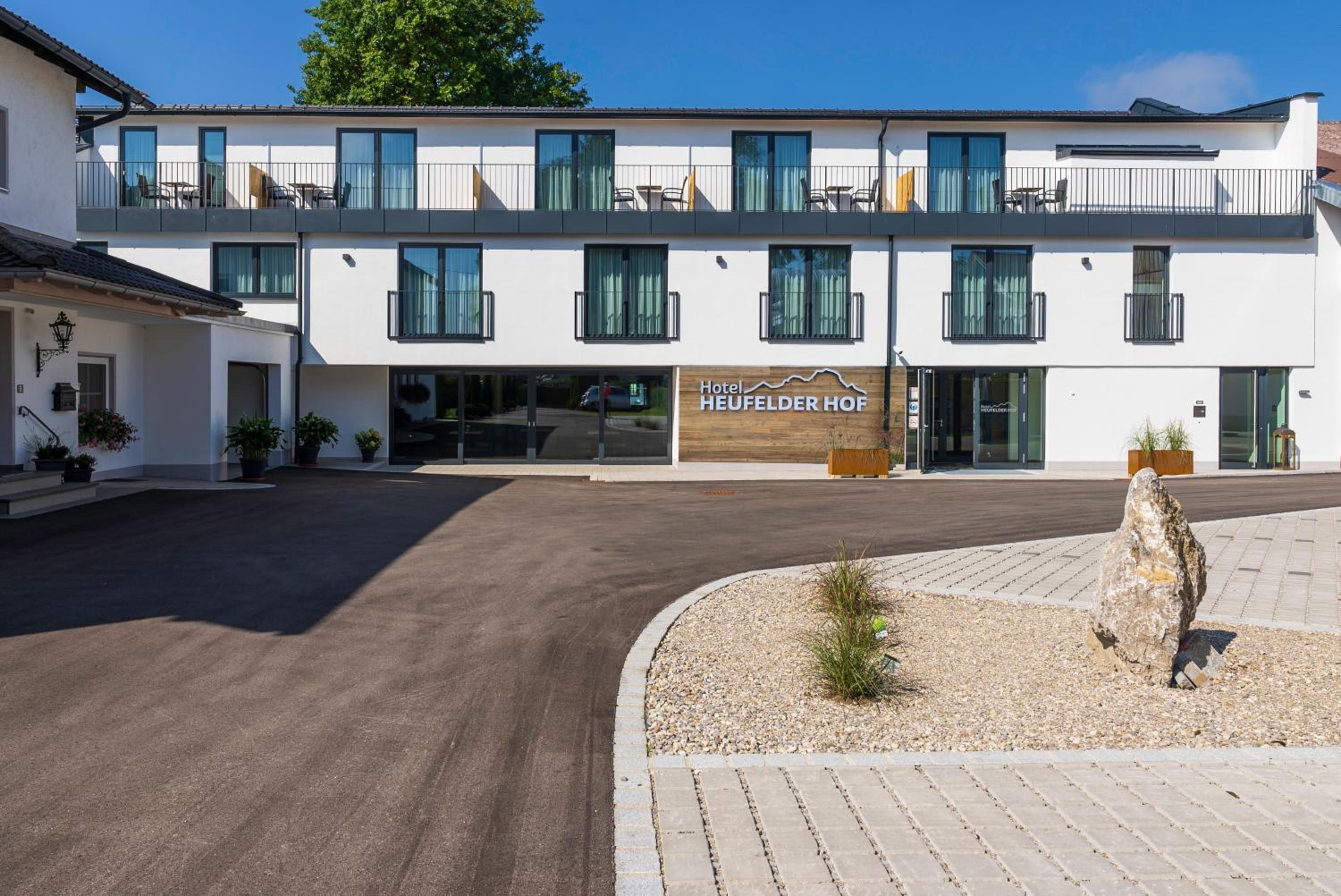 A modern hotel with a flat roof, large windows, and a sign reading 'Hotel HEUFELDER HOF'.