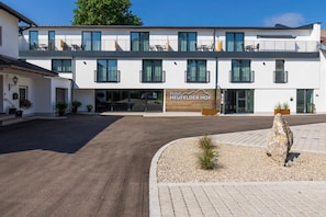 A modern hotel with a flat roof, large windows, and a sign reading 'Hotel HEUFELDER HOF'. - Heufelder Hof (Bruckmuehl)