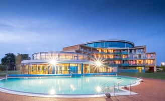 A multi-story hotel with a swimming pool and a glass-enclosed structure.