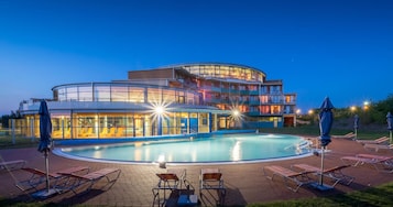 A hotel with a pool, lounge chairs, and a circular deck area.