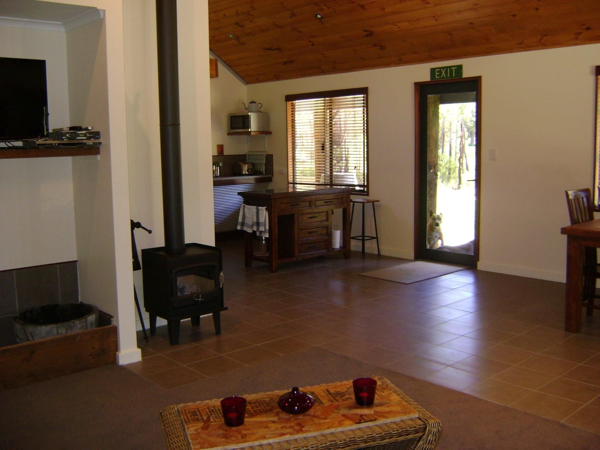 A living room with a fireplace, a television, and a kitchen area with a window.