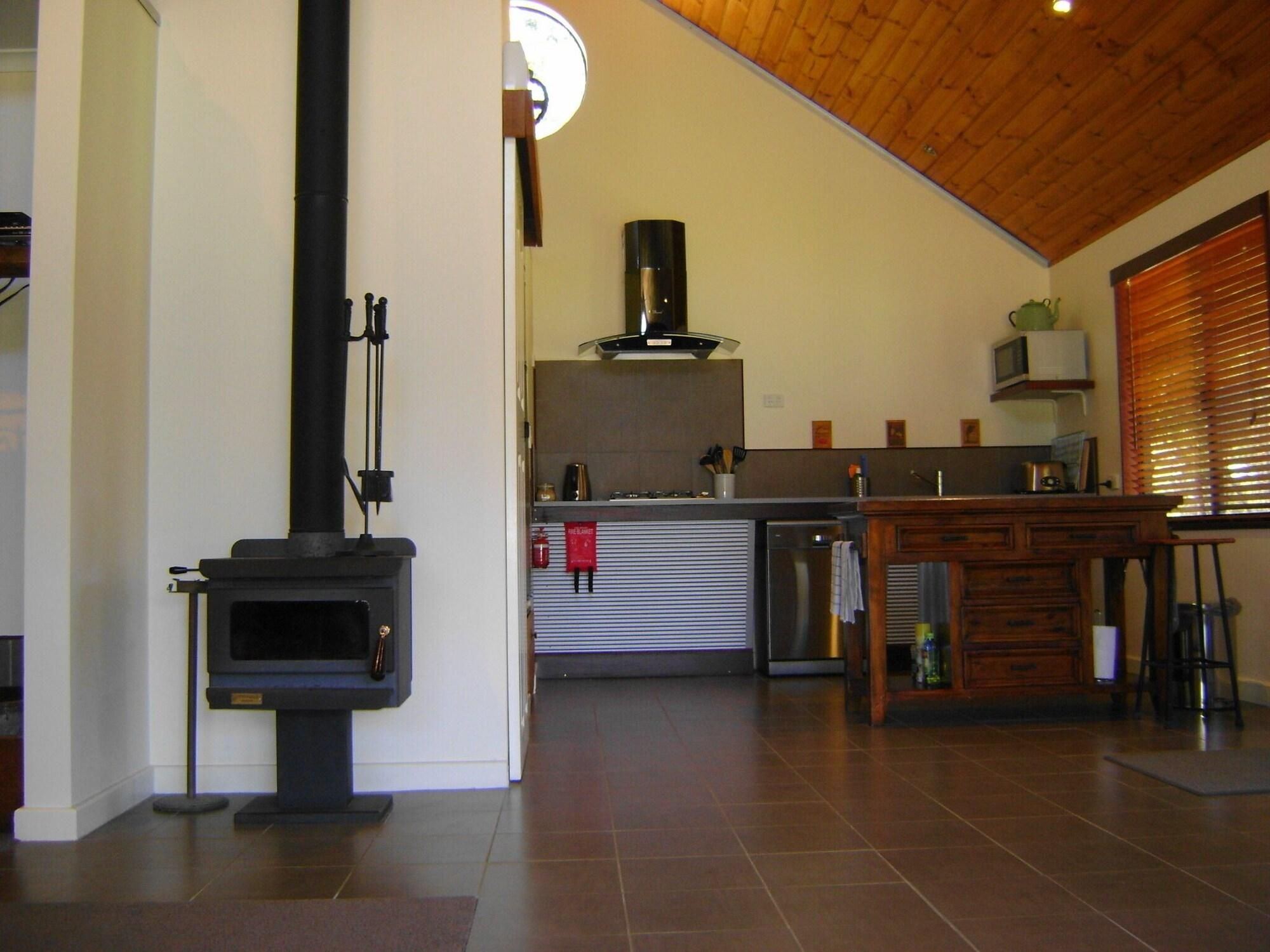 Eine moderne Küche mit Holzofen, einem Edelstahl-Kühlschrank und einem Holztisch.