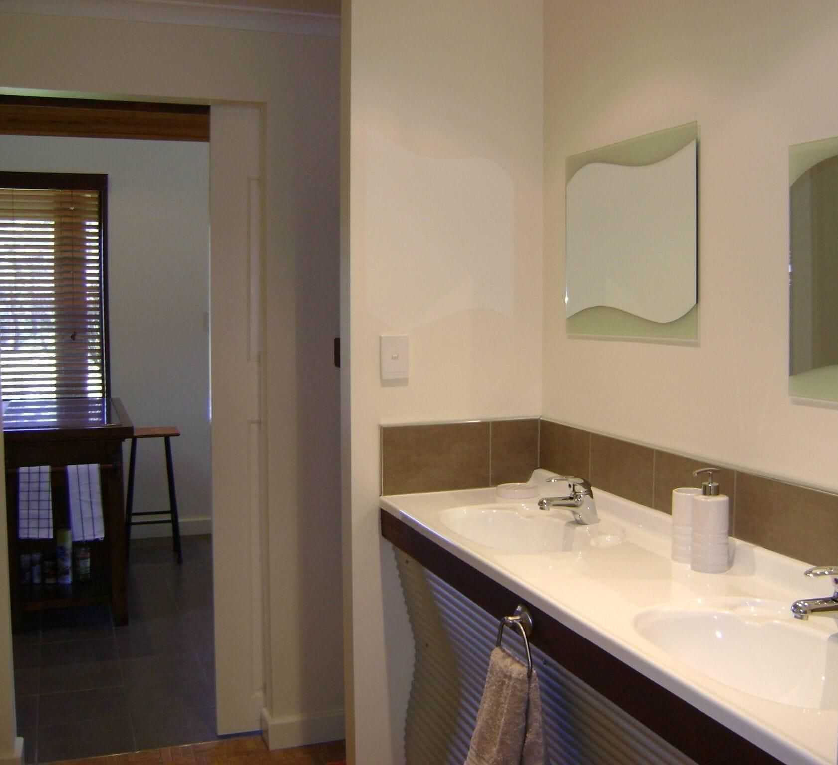 A bathroom with two sinks, a mirror, and a towel rack.