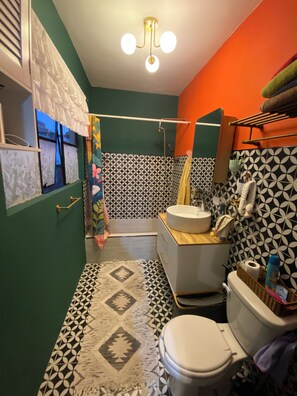 Ein Badezimmer mit einem gemusterten Boden, einer Toilette, einem Waschbecken und einer Duschkabine.