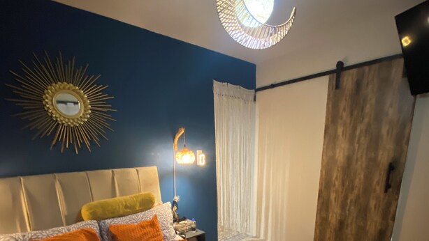 A bedroom with a bed, a nightstand, a wall-mounted mirror, a hanging light fixture, and a sliding door. - Superb 1-bedroom apartment in vibrant Ciudad de México (Ciudad de México)