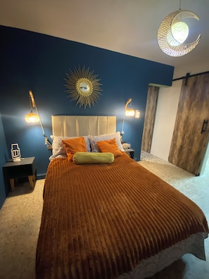 Ein Schlafzimmer mit einem Bett, einem Nachttisch, einer Wandlampe und einem Holzschrank.