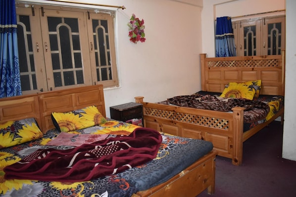 A bedroom with two wooden beds, each with a headboard, a nightstand, and a small table. - Hotel 1947 (Balakot)