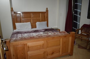 Una cama de madera con cabecera, dos almohadas y una colcha estampada.
