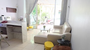 A modern living room with a sofa, ottoman, and a small table with a plant. - Pop 75429 101 Place Navanakorn (Bangkok)