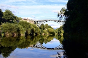 A river with a bridge, surrounded by trees and a building in the background.