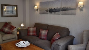A living room with a sofa, two armchairs, a coffee table, and wall-mounted lamps.