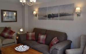 A living room with a sofa, two armchairs, a coffee table, and wall-mounted lamps.