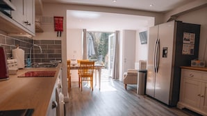 A modern kitchen with a dining area, wooden flooring, and a view to the outdoors.