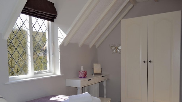 A bedroom with a bed, a window with a view, a wardrobe, and a radiator.