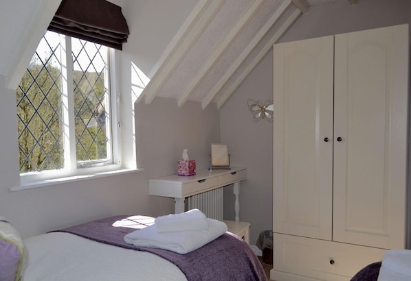 A bedroom with a bed, a window with a view, a wardrobe, and a radiator.