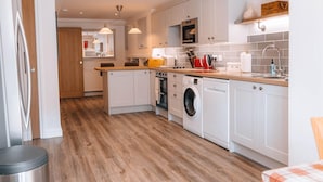 A modern kitchen with white cabinetry, a built-in oven, a washing machine, and a microwave.