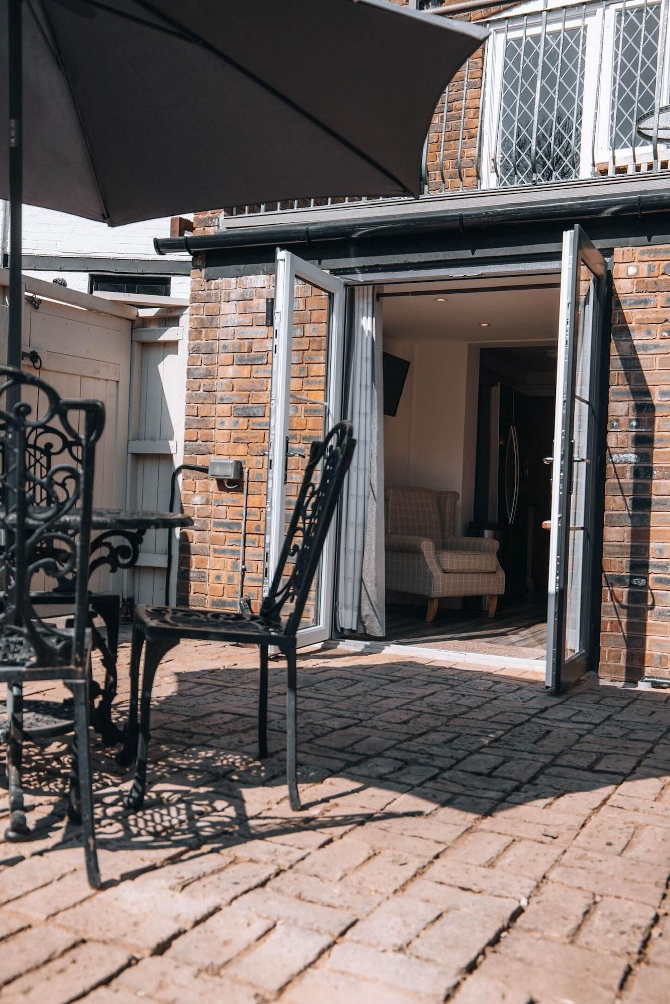 An outdoor seating area with a table and chairs, a covered patio, and a brick building with a window.