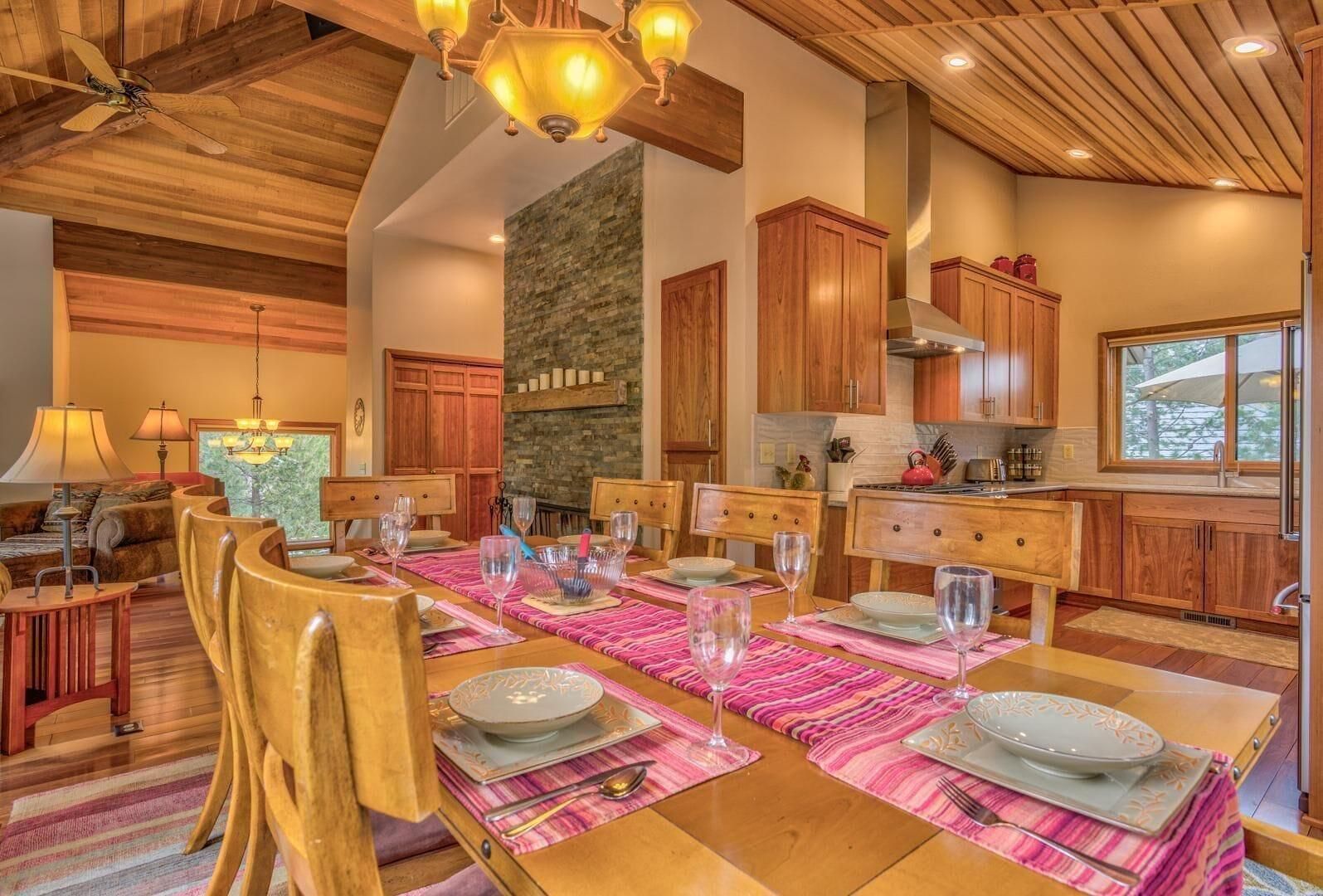 A dining area with a wooden table set for six, surrounded by wooden chairs.