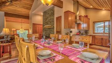 A dining area with a wooden table set for six, surrounded by wooden chairs.