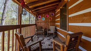 A wooden cabin with a porch, rocking chairs, and a window with blinds. - Cozy Bears Cabin (Pigeon Forge)