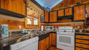 A kitchen with wooden cabinets, a microwave, a dishwasher, and a stove. - Cozy Bears Cabin (Pigeon Forge)