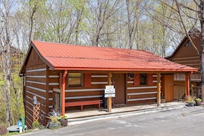 A rustic cabin with a red roof, wooden walls, and a porch with benches. - Cozy Bears Cabin (Pigeon Forge)